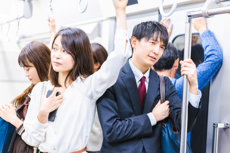 満員電車の中でリュックを前に抱えてすり対策をしている人の写真