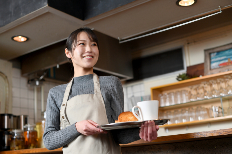 レストランのホールでお客さんに料理を運ぶスタッフの写真