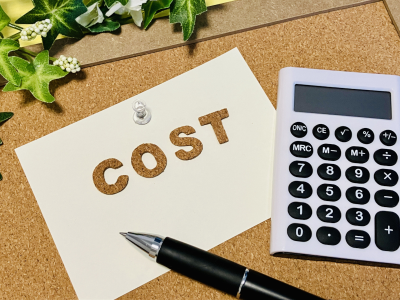 COSTと書かれたメモと電卓、費用シミュレーションのイメージ
