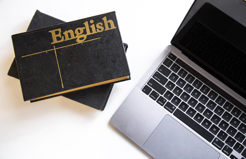 Englishと書かれた本とノートパソコン、英語学習継続のイメージ