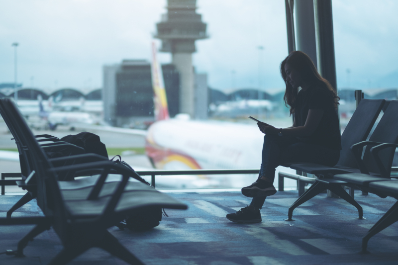 空港でスマートフォンを確認する旅行者の様子