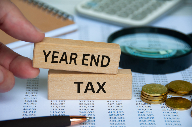 「YEAR END TAX」の木製ブロックと電卓・コイン・書類