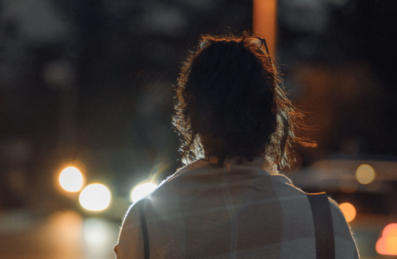 夜の住宅街を歩く人の後ろ姿